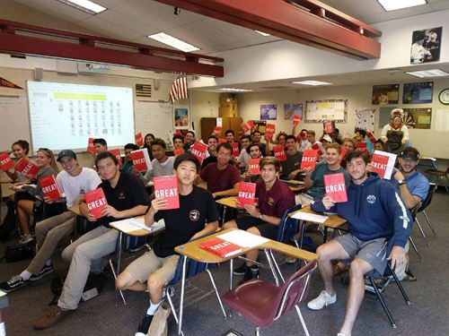 Students in a classroom holding up books that say Great